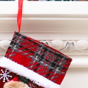 Detailaufnahme der rot-schwarzen Karo-Weihnachtssocke mit weißem Plüschrand und Schneeflocke