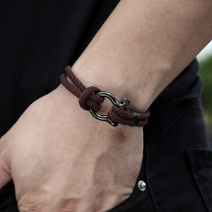 Close-up of men's braided dark brown cord bracelet with black horseshoe shackle clasp