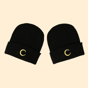 Pair of black knit beanies with yellow moon embroidery in a minimalist flat lay