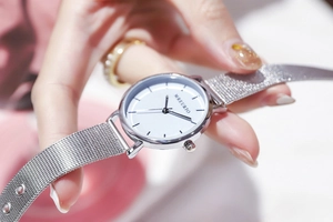 Close-up of elegant women silver Milanese mesh watch with white dial and metal indices
