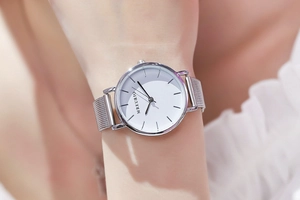Detail of silver Milanese mesh strap watch on woman's wrist with lace sleeve