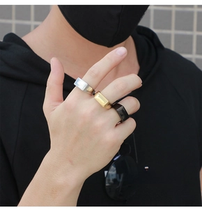 Detail of three minimalist rectangular signet rings in gold, silver and black finishes