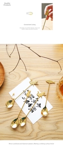 Detailed view of 4 gold stainless steel cat and fish handle spoons on a wooden table