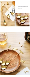 Close-up of golden stainless steel cat-shaped dessert spoons on a wooden table