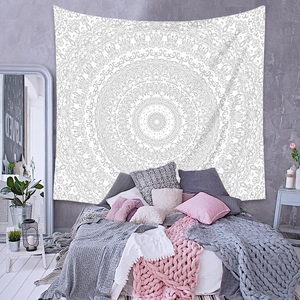 Détail de la tapisserie mandala blanche avec motifs géométriques gris sur un mur texturé