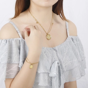 Parure de bijoux en acier titane doré avec pendentifs ronds portée par un mannequin