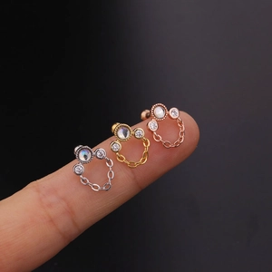 Dettaglio di orecchini a vite in argento, oro e oro rosa con pietre di zircone incastonate