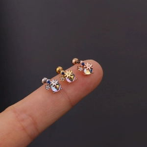 Dettaglio di tre orecchini a tema pianeta in argento, oro e oro rosa indossati sulle dita