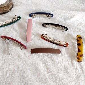 Minimalist matte acrylic spring hair clips set in various colors on white fabric