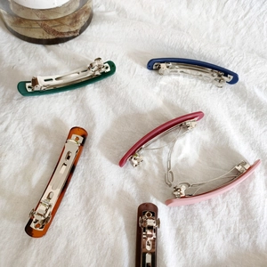 Minimalist matte acrylic spring hair clips in various colors on a white fabric background