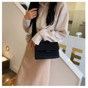 Detail of black matte leather crossbody bag with wide nylon strap on model