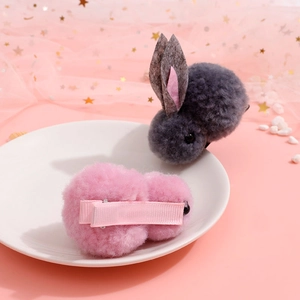 Cute plush bunny hair clips in pink and grey colors on a white decorative plate