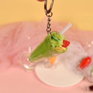 Detail of a mini green smoothie keychain with a red strawberry charm and silver metal ring