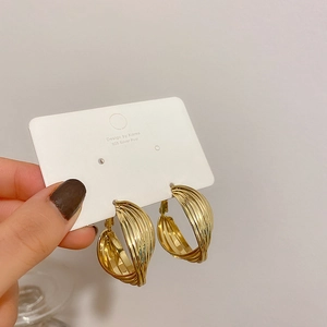 Close-up of gold geometric twisted multi-layer hoop earrings with 925 silver needles
