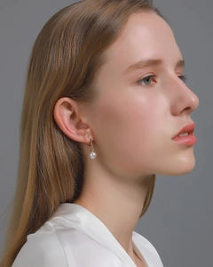 Detailed view of a gold pearl ear cuff worn on the earlobe without any piercing