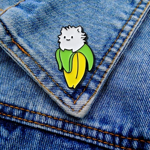 Close-up of a cute cartoon enamel banana cat pin on blue denim jacket fabric