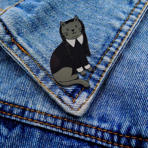 Detail of cute cat enamel pin inspired by Wednesday Addams on a denim jacket pocket