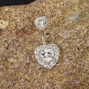Piercing ombelico a cuore in argento con zirconi luccicanti su sfondo di roccia naturale