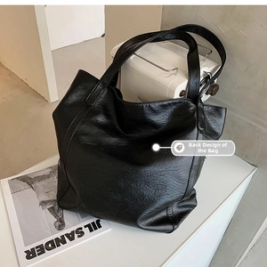 Detailed back design of a large black textured leather tote bag with rivet accents