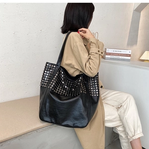 Lifestyle shot of large black leather tote bag with silver rivets worn by a model