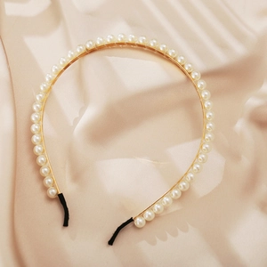 Elegant gold metal headband with white faux pearls on champagne silk background