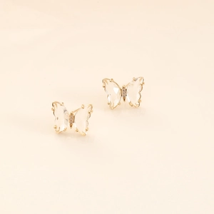 Macro detail of butterfly stud earrings featuring golden frame and clear zircon stones