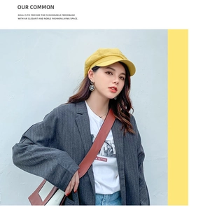 Outdoor shot of a bright yellow cotton linen newsboy hat with stylish checkered earrings