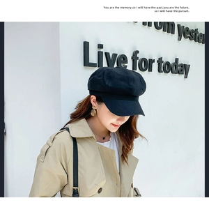 Close-up of a black cotton linen octagonal newsboy hat worn by a model in a street style view