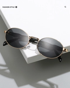 Detailed macro view of trendy oval sunglasses with a sleek gold metal frame and dark lenses