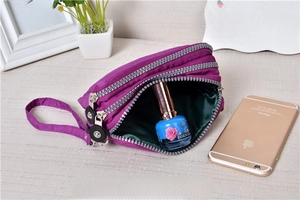 Detail of purple washed denim pouch with three zip compartments and hand strap