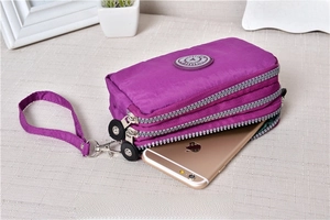 Detailed view of purple nylon pouch featuring a triple zipper design and wrist strap
