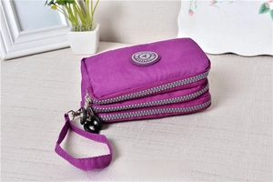Close-up of a purple multi-layer nylon wristlet pouch with three zipper compartments