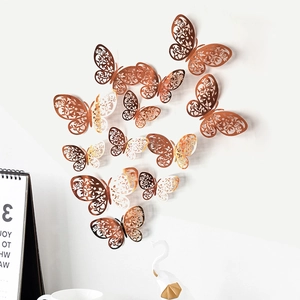 Macro detail of 12 rose gold and gold gradient hollow butterfly wall stickers on a white wall