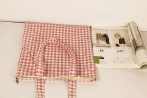 Detail of red gingham canvas tote bag showing the secure metal zipper and fabric texture