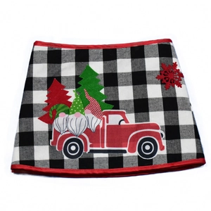 Détail du cache-pied de sapin avec motif écossais, camion rouge et nains brodés