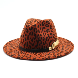 Leopard print wool fedora hat with a black band and gold leaf charm on white background