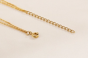 Detail of golden double-layer necklace showing secure spring clasp and extension chain