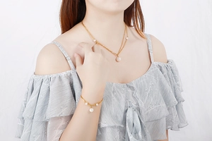 Detail of double-layer gold stainless steel necklace and pearl bracelet worn by model