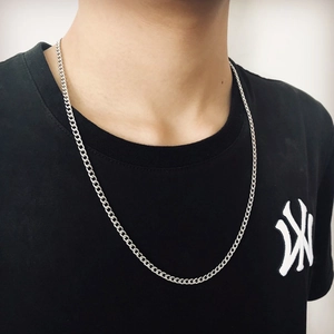 Detailed view of a slim silver Cuban link chain necklace worn on a male model neck