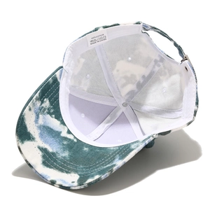 Détail d'une casquette en coton tie-dye bleu montrant l'étiquette coton et la boucle