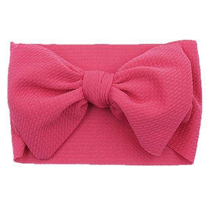 Detail view of pink bow baby headband with textured knit fabric on white background