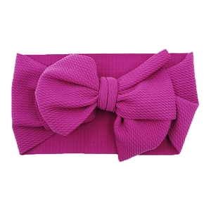 Macro detail of infant headband featuring rose red waffle textured fabric and large bow