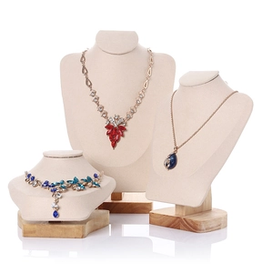 Three tiered beige velvet jewelry busts with wooden bases displaying colorful crystal necklaces