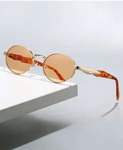 Detail view of oval metal sunglasses with golden frame and amber tortoiseshell temples