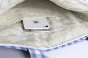 Detail of blue checkered crossbody bag lining with floral pattern and phone pocket