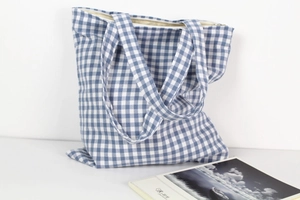 Detail of blue gingham canvas tote bag showing white zipper closure and interior lining