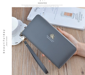 Grey pebbled leather wallet featuring a clover logo, wrist strap, and double zippers
