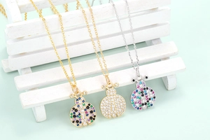Close-up of ladybug necklaces with colorful zircon stones on a white miniature bench