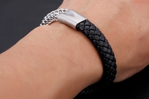 Macro shot of a black braided leather bracelet with silver stainless steel chain detail