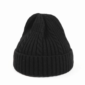 Close-up of black cable knit beanie showing thick ribbed texture and soft fabric